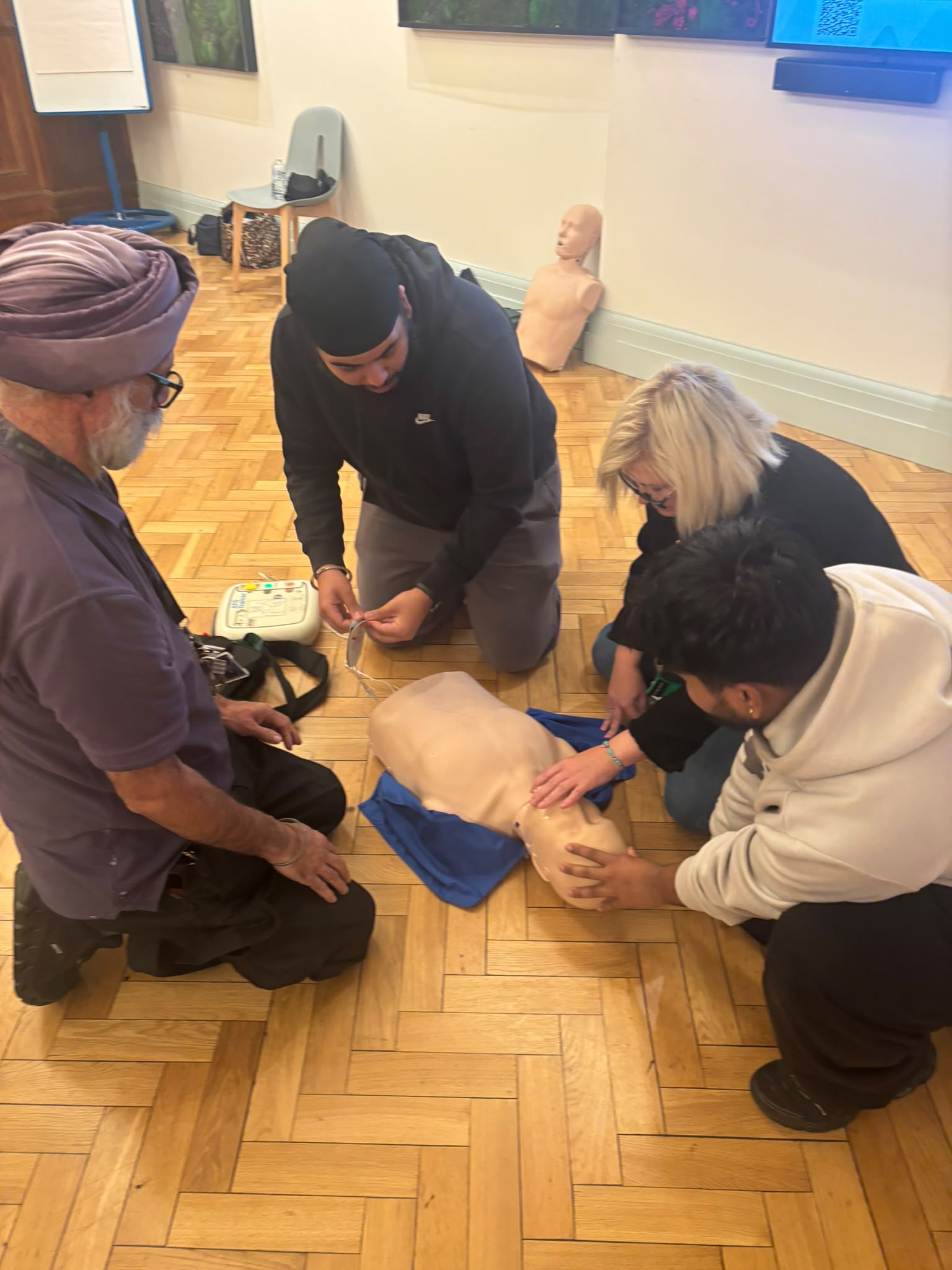 Preparing AED trainer pads beside a CPR manikin during school first aid training